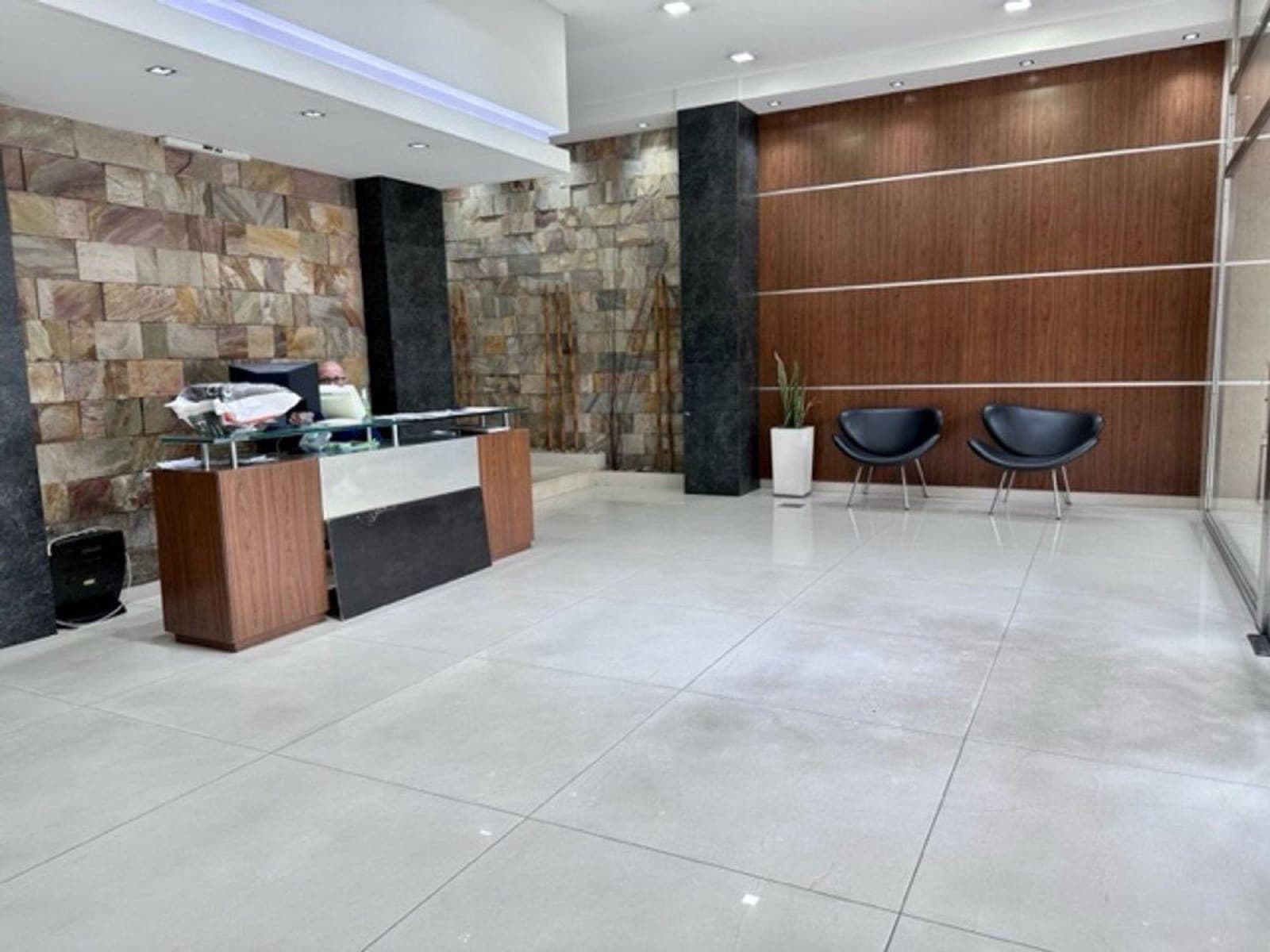Recepción del edificio revestida en piedra natural, con estar de espera